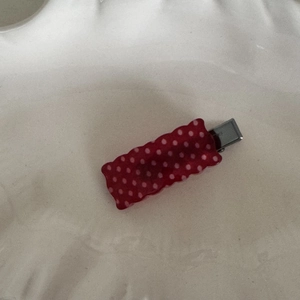 Detail view of a red polka dot rectangular hair clip with a silver metal duckbill clamp