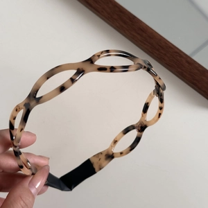 Detail of tortoise shell acetate headband featuring hollow oval links and non-slip ends