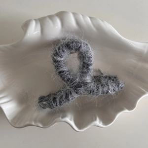 Detalle de pinza para el pelo de pelo sintético gris en una bandeja de cerámica
