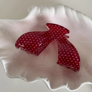 Detailed view of a red hair claw with white polka dots on a shell decorative tray