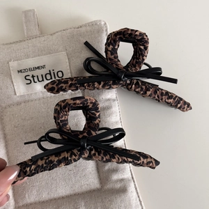 Detail showing leopard print fabric hair claw clips with black leather bow accents