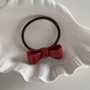 Dettaglio elastico per capelli con fiocco in acetato bordeaux e logo dorato France Handmade
