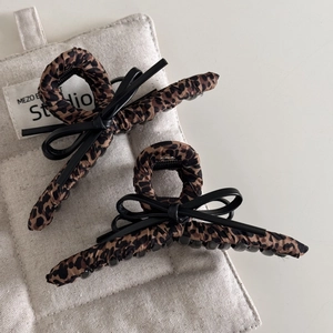 Detail of leopard print hair claw clips with black leather bows on canvas background