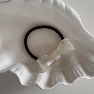 Dettaglio dell'elastico per capelli con fiocco in acetato e timbro dorato fatto a mano