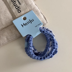 Detailed view of elastic blue hair ties set on a display card over a linen background