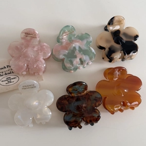 Vue détaillée de pinces à cheveux fleur en acétate en six couleurs avec fini marbré