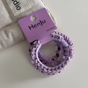 Detailed view of elastic purple hair scrunchies set on display card with soft fabrics