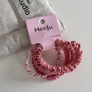 Detailed view of pink hair tie set featuring ruffled scrunchies and twisted elastic bands