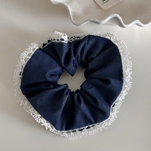 Detailed macro view of dark navy blue scrunchie with delicate white lace trim
