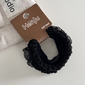 Detailed close-up of high elasticity black hair band with lace texture on display card