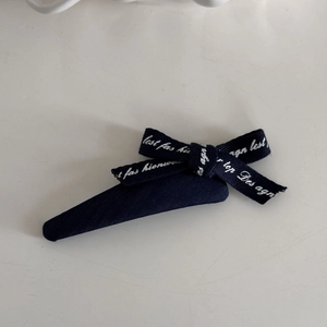 Detail of navy blue bow hair clip with white lace patterns and stylish metal duckbill clip