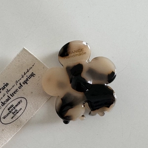 Détail de la pince à cheveux fleur en acétate avec motif écaille et logo doré