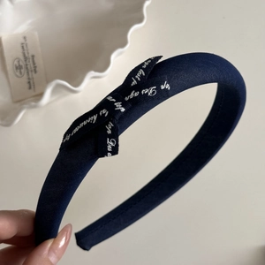 Detailed view of navy blue bow hair clip with white French lettering on premium fabric