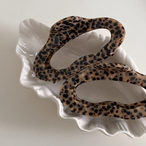 Set of two wavy leopard print acetate hair claws in a white shell display dish