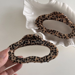 Detail of hollow oval tortoiseshell acetate hair claw clip held by hand for size scaling