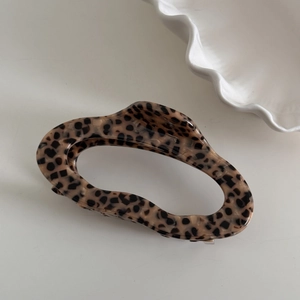 Detail of tortoise shell acetate claw clip with hollow wavy design and glossy finish