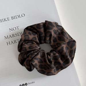 Close-up of leopard print scrunchie with twill texture fabric on a white book