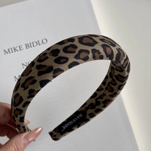 Detail of handmade leopard print wide headband featuring a luxury fabric texture and label