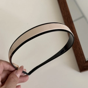 Detail of minimalist beige and black headband with high-gloss finish and mirror effect