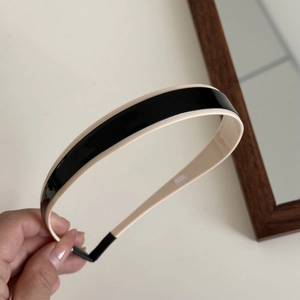 Close-up of a two-tone headband in glossy black and cream resin with anti-slip ends