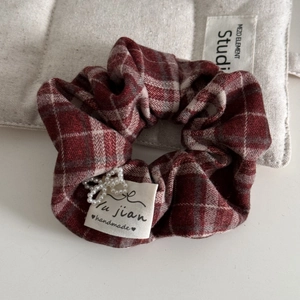 Detail of red plaid scrunchie with faux pearl flower and a handmade fabric label