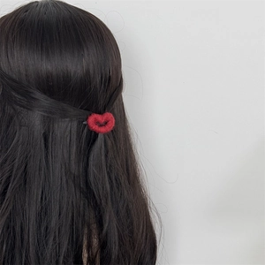 Detailed view of a red knitted heart hair clip worn as a stylish accent on dark hair