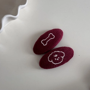Détail de barrettes tricotées bordeaux avec broderie blanche d'os et de chiot mignon