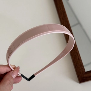 Close-up of pink glossy headband with comfortable black non-slip ends held by hand