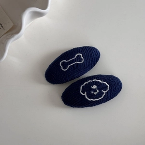 Gros plan détaillé des barrettes en tricot bleu marine avec broderie os et chiot mignon