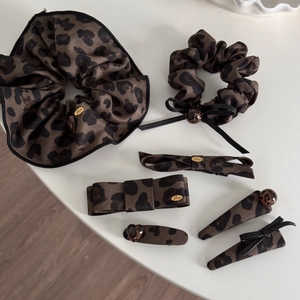 Flat lay of leopard print hair accessories set with bows and golden metal charms