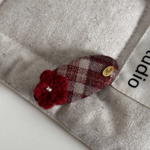 Detail of red checkered hair clip with hand-crocheted flower and gold Love tag