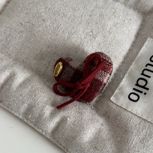 Detailed macro view of heart-shaped plaid fabric hair clip with a golden Love button