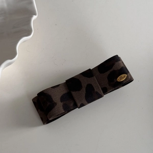 Close-up of leopard print bow hair clip with gold metal plate engraved with Love