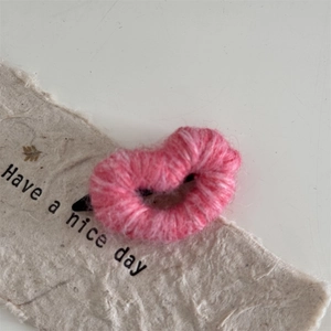 Detail of pink knitted heart hair clip with cozy wool texture and secure metal snap