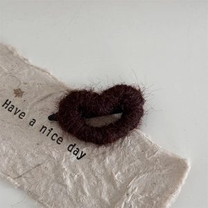 Detail of a brown fuzzy heart-shaped hair clip on artisanal paper with a cozy autumn vibe