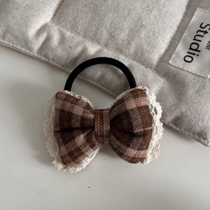 Detail of red and brown plaid bow hair clip with white lace trim for women accessories