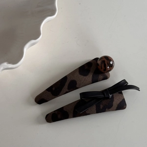 Detail view of leopard print hair clip set with marble bead and black leather bow