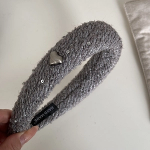 Détail d'un serre-tête en tweed gris avec cœur argenté et étiquette faite main