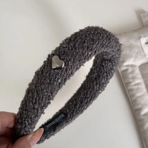 Gros plan d'un serre-tête en tissu gris foncé avec paillettes cœur argentées et étiquette