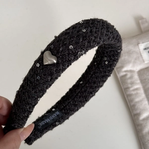 Détail du serre-tête en tweed noir avec paillettes argentées et breloque en forme de cœur