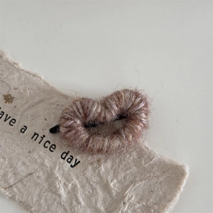 Close-up of brown knit heart hair clip with cozy wool texture and metal clip detail