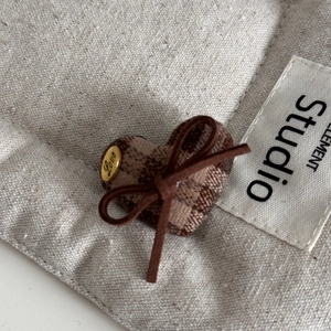 Detailed close-up of a heart-shaped fabric clip featuring a vintage brown plaid pattern