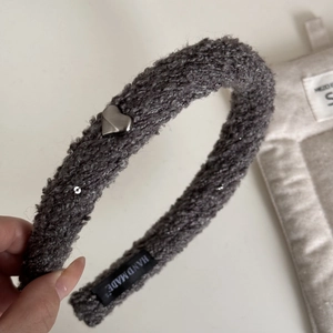 Détail du serre-tête en tricot gris avec cœur argenté et étiquette faite main