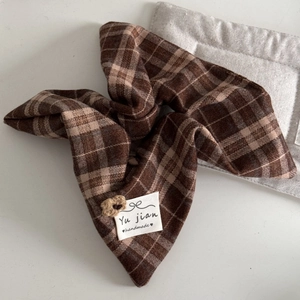 Detail of a brown checkered fabric hair scrunchie with a white handmade sewing label