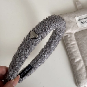 Détail d'un serre-tête en tricot gris avec paillettes argentées et breloque en forme de cœur