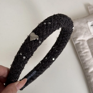 Détail d'un serre-tête en tweed noir avec paillettes argentées et breloque cœur