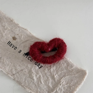 Detailed view of dark red knitted heart hair clip with black metal alligator base