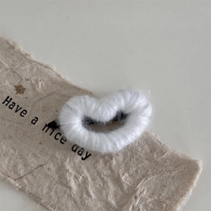 Close-up of white knitted heart hair clip on decorative paper with metal duckbill clip