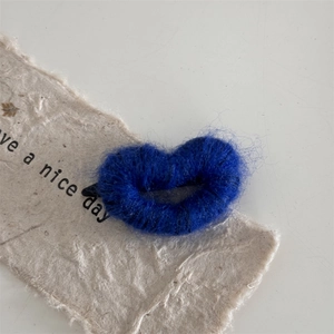 Macro detail of plush deep blue heart hair clip with soft texture on handmade paper
