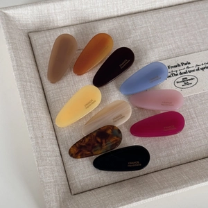 Set of 10 teardrop acetate hair clips in amber and macaron colors on a linen tray